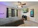 Bedroom with a ceiling fan, two windows, a television, and a full-length mirror on the door at 6225 Scarlet Darter Way, Tampa, FL 33625