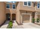 Beige two-story home featuring an attached garage, small front garden, and covered front entryway at 6225 Scarlet Darter Way, Tampa, FL 33625