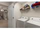 Practical laundry room with a washer, dryer, and shelving for storage, next to a hallway at 6225 Scarlet Darter Way, Tampa, FL 33625