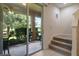 View from inside the house of the screened in patio, featuring multiple potted plants, through a large glass sliding door at 6225 Scarlet Darter Way, Tampa, FL 33625