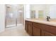 This bathroom features a glass shower, wood vanity and tile flooring at 711 Parker Den Dr, Ruskin, FL 33570