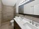 Modern bathroom featuring double sinks, updated lighting, and a luxurious tiled shower at 8114 Pond Shadow Ln, Tampa, FL 33635