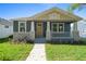 Charming home featuring a covered porch, stone accents, fresh landscaping, and a welcoming yellow front door at 936 57Th N Ave, St Petersburg, FL 33703