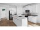 A modern kitchen with stainless steel appliances, white cabinetry, and a granite island with a sink at 936 57Th N Ave, St Petersburg, FL 33703