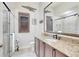 Bathroom with granite countertop, wood cabinetry, frameless shower, and decorative mirror creating a luxurious feel at 9630 Tree Tops Lake Rd, Tampa, FL 33626