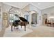 Elegant living area with a grand piano, arched doorways, and sophisticated decor creating a luxurious atmosphere at 9630 Tree Tops Lake Rd, Tampa, FL 33626