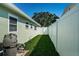 Narrow backyard with lush green grass, a white privacy fence, and visible pool equipment for convenient maintenance at 12901 129Th Ave, Largo, FL 33774