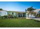 Attractive single-story home with a well-kept lawn, vibrant flowerbeds, and a quaint seating area by the entrance at 12901 129Th Ave, Largo, FL 33774