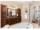 Elegant bathroom with granite countertops, a soaking tub, dark wood cabinets, and decorative mirrors at 10614 Low Oak Terrace, Thonotosassa, FL 33592