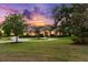 Stunning exterior view of home featuring beautiful landscaping, circular drive, and stone accents under a colorful sky at 10614 Low Oak Terrace, Thonotosassa, FL 33592
