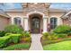 Close-up of the front entrance with stone archway, decorative iron door, and lush landscaping at 10614 Low Oak Terrace, Thonotosassa, FL 33592