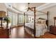 Main bedroom featuring a four-poster bed, hardwood floors, a ceiling fan, and french doors at 10614 Low Oak Terrace, Thonotosassa, FL 33592