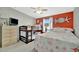 bedroom featuring a bunk bed, queen bed, dresser and starfish wall hangings against bright orange accent wall at 119 E Saint Johns Way, Apollo Beach, FL 33572