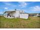 Rear exterior of home, showcasing storage shed, lawn and carport with golf cart under a cloudy sky at 119 E Saint Johns Way, Apollo Beach, FL 33572