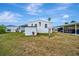 Exterior view of home and shed with lawn, landscaping, and carport with golf cart at 119 E Saint Johns Way, Apollo Beach, FL 33572