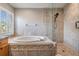 Bright bathroom featuring soaker tub, tiled walk-in shower and natural light at 12712 Stanwyck Cir, Tampa, FL 33626