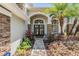 Inviting entrance with double doors, stone pillars, and lush landscaping creating a welcoming atmosphere at 12712 Stanwyck Cir, Tampa, FL 33626
