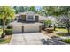 Beautiful two-story home with stone accents, a large driveway, and mature trees providing shade and curb appeal at 12712 Stanwyck Cir, Tampa, FL 33626