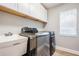 Functional laundry room equipped with a modern washer and dryer and storage cabinets at 12712 Stanwyck Cir, Tampa, FL 33626