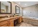 Main bathroom featuring double sinks, granite counters, tiled tub surround and walk-in shower at 12712 Stanwyck Cir, Tampa, FL 33626