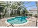 Screened-in pool area showcasing a refreshing pool, hot tub, a grill, and lots of lush green trees at 12712 Stanwyck Cir, Tampa, FL 33626