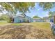 The backyard with lush grass, partial view of a guest cottage, palm trees, and privacy fence at 1322 Idlewild Dr, Clearwater, FL 33755