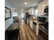 An open kitchen features stainless steel appliances, white cabinets, and wood flooring leading to the living room at 1322 Idlewild Dr, Clearwater, FL 33755