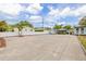 Large paved parking area with ample space, surrounded by a white fence and palm trees at 1322 Idlewild Dr, Clearwater, FL 33755
