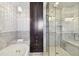 Marble bathroom featuring soaking tub, glass shower, and a tall storage cabinet at 17 Bellevue Dr, Treasure Island, FL 33706