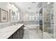 Bright bathroom featuring dual sinks, soaking tub, glass enclosed shower, and mosaic flooring at 17 Bellevue Dr, Treasure Island, FL 33706
