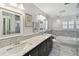 Bright bathroom showcasing marble counters, dual sinks, soaking tub and mosaic tile flooring at 17 Bellevue Dr, Treasure Island, FL 33706