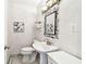 Quaint half bath with pedestal sink, framed mirror, sconce lighting and decorative wallpaper at 17 Bellevue Dr, Treasure Island, FL 33706