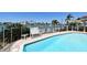 Backyard pool overlooks canal featuring lush plants, white chairs and a clear blue sky at 17 Bellevue Dr, Treasure Island, FL 33706
