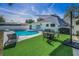 A beautiful backyard with a swimming pool, sleek artificial turf, lounge chairs, and a fire pit at 1710 Hibiscus N Cir, Oldsmar, FL 34677