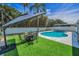 Well-maintained backyard with a refreshing pool, cozy fire pit area, and lush artificial turf at 1710 Hibiscus N Cir, Oldsmar, FL 34677