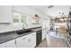 Bright kitchen with black dishwasher and countertops, white cabinets, and a view of the dining area at 1710 Hibiscus N Cir, Oldsmar, FL 34677