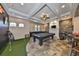A spacious game room featuring a pool table, putting green, stone wall and modern lighting at 18423 Lithia Towne Rd, Lithia, FL 33547