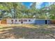A spacious backyard with a white house and a blue shed beneath a lush tree canopy at 2003 E Clinton St, Tampa, FL 33610