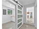 Hallway featuring a modern barn door with frosted glass panels and a view into the kitchen area at 2003 E Clinton St, Tampa, FL 33610