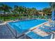 A community pool with blue lounge chairs and umbrellas, perfect for relaxation and fun in the sun at 209 Woodlake Wynde, Oldsmar, FL 34677