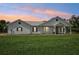 Inviting exterior of single-story home with metal roof, complemented by manicured lawn at sunset at 21019 Lonesome Acre Rd, Wimauma, FL 33598