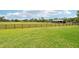 Green pasture with wooden fence surrounding the area, with a horse barn at 21019 Lonesome Acre Rd, Wimauma, FL 33598