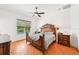 Spacious main bedroom features a ceiling fan, wood floors, and a picturesque view of the outdoor pool at 21019 Lonesome Acre Rd, Wimauma, FL 33598