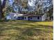 The backyard of this single Gathering house features lush grass and is surrounded by mature trees at 37654 Eiland Blvd, Zephyrhills, FL 33542