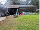 Fenced backyard with patio, grill, picnic table, ladder, and enclosed screened-in pool area at 37654 Eiland Blvd, Zephyrhills, FL 33542