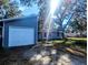 View of the one-story home with an attached garage and a driveway, surrounded by mature trees at 37654 Eiland Blvd, Zephyrhills, FL 33542