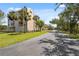 Road leading to a condo complex, featuring palm trees, green lawns, and a sunny day in a neighborhood at 6205 Shoreline Dr # 1204, St Petersburg, FL 33708