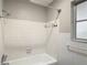 Bright bathroom with white tile, featuring a shower-tub combination and a window that provides natural light at 7280 Tarrytown Dr, Spring Hill, FL 34606