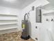 Utility room features a hot water tank, shelving, and white walls at 7280 Tarrytown Dr, Spring Hill, FL 34606