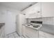 Galley kitchen featuring white appliances, white cabinetry and tile backsplash at 8402 Woodlake Dr, Tampa, FL 33615